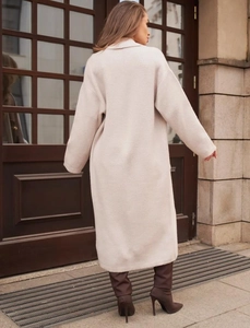 Vista posteriore del lungo cardigan in maglia crema che mostra il drappeggio elegante