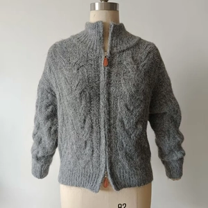 Close-up of gray cable-knit sweater texture with dual zippers and soft plush wool finish