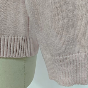Détail d'un cardigan en tricot rose montrant les coutures fines et les poignets