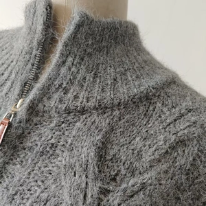 Close-up of fluffy grey alpaca knit cardigan with textured zipper and leather puller detail