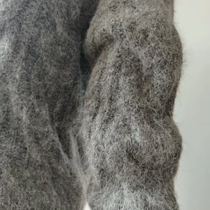 Close-up of soft grey alpaca wool knit fabric showing fluffy texture and premium fiber detail