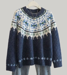Detailed knit texture of Fair Isle navy sweater with green pom-poms and winter jacquard
