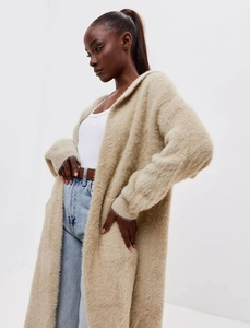 Detailed close-up showing the soft plush texture of the long beige knit cardigan coat