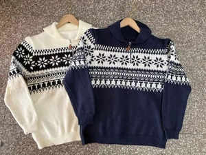 Detail of soft knit sweater showing polo collar with zipper and Nordic snowflake jacquard pattern