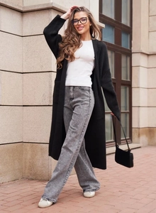 Scatto street style di un lungo cardigan nero a maglia con jeans a gamba larga