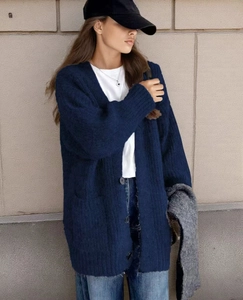 Detail of dark blue knit cardigan showing plush texture and ribbed cuffs on street model