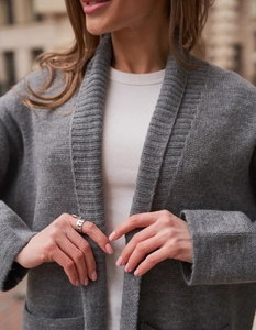 Dettaglio ravvicinato del cardigan in maglia grigio scuro con trama in lana e collo a scialle