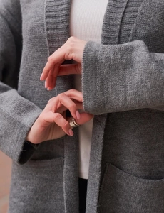 Dettaglio della trama a maglia grossa e polsini a costine di questo lungo cardigan grigio