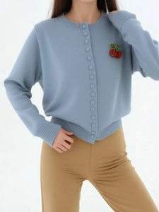 Detail view of light blue knit cardigan with red cherry embroidery and round neck buttons