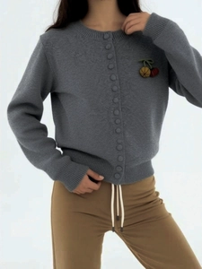 Detail of grey knit cardigan featuring delicate cherry embroidery and ribbed texture