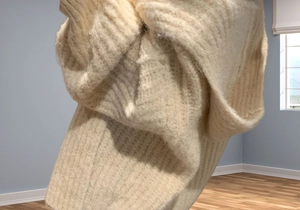 Detailed view of thick cream ribbed knit texture on a soft alpaca-style winter sweater