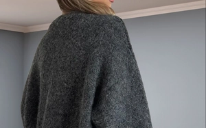 Rear view of a loose dark gray knitted cardigan with soft textured lantern sleeves