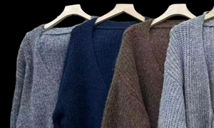 Close-up of knit cardigans in multiple colors with soft faux alpaca texture and V-neck line