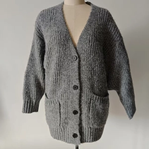 Detail of grey V-neck ribbed knit cardigan featuring dark buttons and soft plush texture