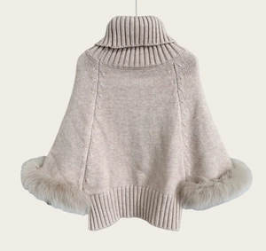 Detail of high-neck beige knit poncho sweater featuring textured ribbed knit and fox fur cuffs