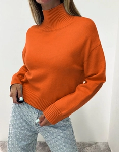 Detailed view of bright orange turtleneck sweater with ribbed cuffs and drop shoulder knit