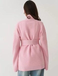 Detail of light pink ribbed knit cardigan showing back waist belt and texture