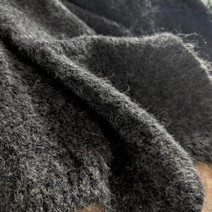 Close-up detail of soft dark grey mohair knit fabric showing plush texture and fiber