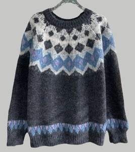 Detailed view of Fair Isle jacquard patterns on a soft grey knit Christmas sweater