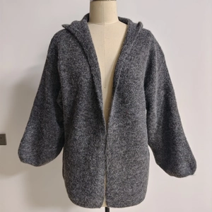 Close-up of grey hooded knit cardigan with plush texture and chunky winter fabric