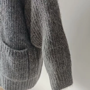 Close-up of soft grey knit cardigan with fuzzy texture and ribbed pocket detail