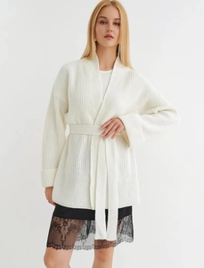 Close-up of chunky knit cardigan texture with tie-waist detail in soft white wool