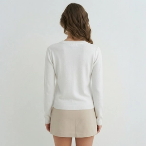Rear view of woman in white crew neck sweater and beige mini skirt for fall season