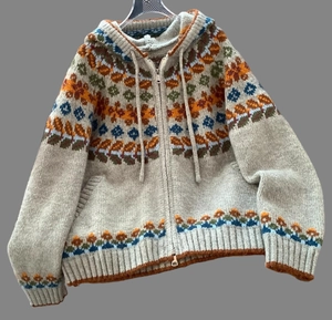 Detail of hooded knit cardigan featuring ethnic jacquard patterns and a front metal zipper