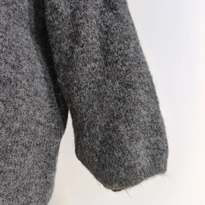 Close-up of thick grey fuzzy knit fabric showing soft long fiber texture on cardigan