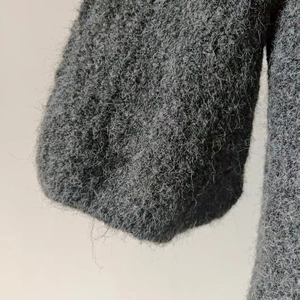 Detail of dark grey lantern sleeve cuff showing soft fuzzy mohair knit texture