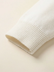 Close-up of ivory crewneck knit sweater ribbed cuff detail with soft fabric texture