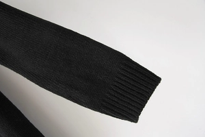 Close-up of the ribbed cuff detail on a soft black knitted long sleeve sweater