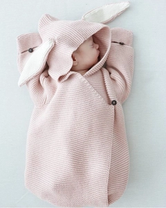 Detail of newborn sleeping bag with cute rabbit ears and rustic wooden buttons