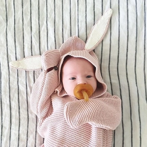 Close-up of pink knitted baby sleeping bag with cute long rabbit ears and soft texture