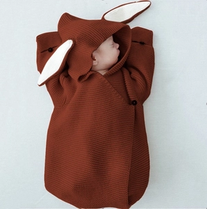 Close-up of baby knitted sleeping bag with cute rabbit ears and black button detail