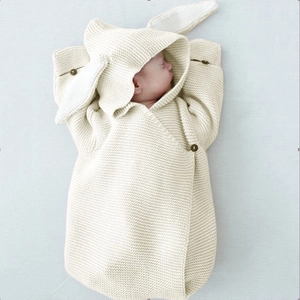 Close-up of cream knit baby sleeping bag with bunny ears and wooden buttons