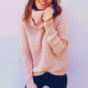 Detail of soft pink turtleneck knit sweater with chunky texture and loose drop shoulders