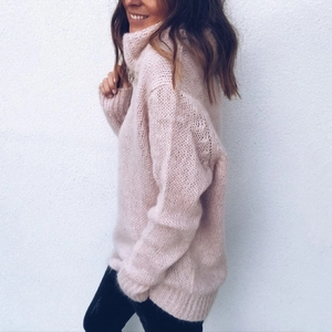 Side view of soft chunky knit fabric and high turtleneck detail on a beige sweater