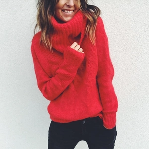 Detail of red oversized turtleneck sweater showing chunky knit texture and ribbed cuffs