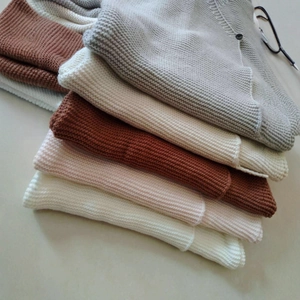 Stacked waffle knit baby sweaters in neutral tones with cute rabbit ear hood details