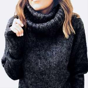 Close-up of a chunky black cowl neck sweater with thick knitted texture and long sleeves