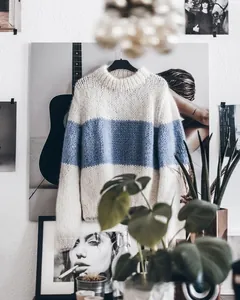 Close-up of loose knit mohair sweater texture with blue stripe detail and ribbed cuffs