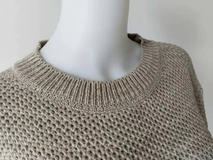 Detail of round neckline and chunky honeycomb knit texture on a khaki sweater