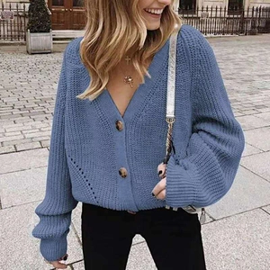 Blue chunky knit cardigan featuring V-neckline and large marble buttons on street background
