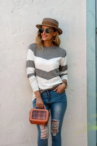 Outdoor shot of a striped knitted sweater paired with ripped jeans and trendy accessories