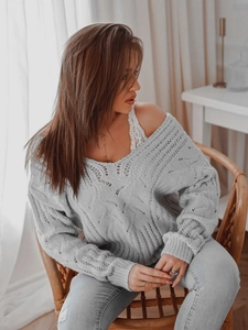 Detailed close-up of light blue V-neck knit sweater with hollow out pattern and lace vest