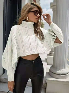 Detail of white high neck cable knit sweater featuring chic split cuffs and cropped hem
