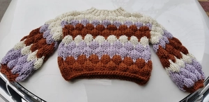 Macro detail of thick chunky knit texture in beige, purple and caramel wavy pattern