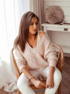 Detailed close-up of chunky cable knit texture on a beige V-neck sweater with lace detail