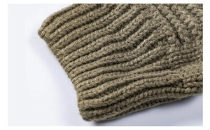 Close-up of olive green cable knit sweater featuring thick ribbed texture and elastic cuff